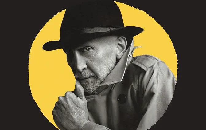 Frank Miller, con sombrero negro y gabardina, se apoya la barbilla en la mano sobre un fondo amarillo